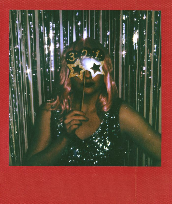 Woman celebrating New Year's Eve with glittering decor and festive props.