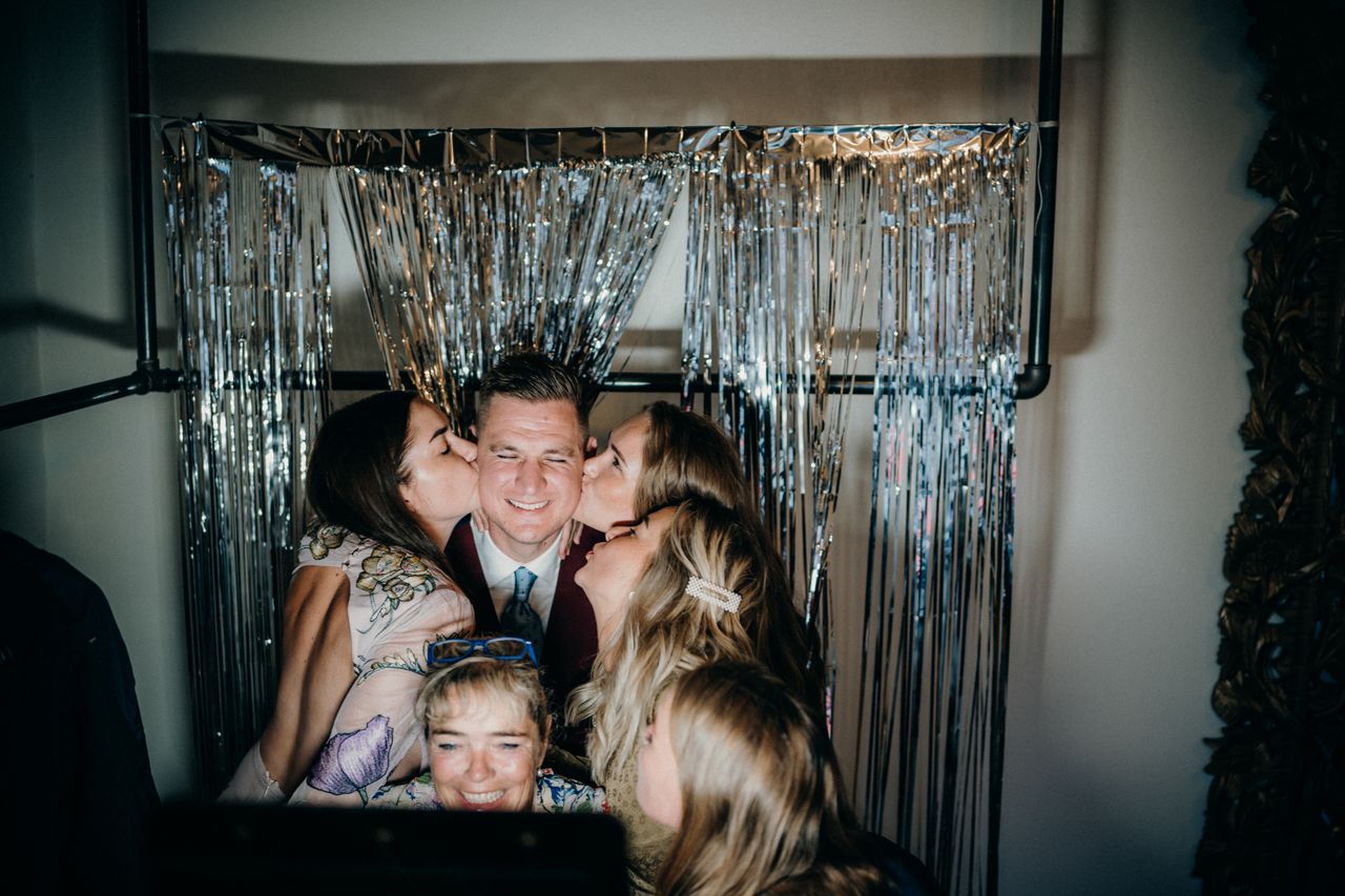 Group enjoying a fun photobooth moment at an indoor party with friends.